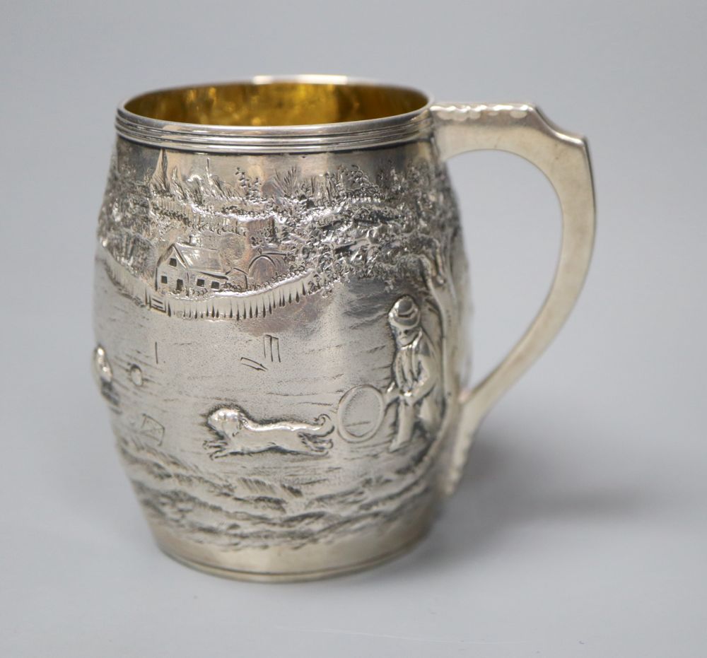 A George III silver barrel shaped christening mug, embossed with figures at play in woodland scene,